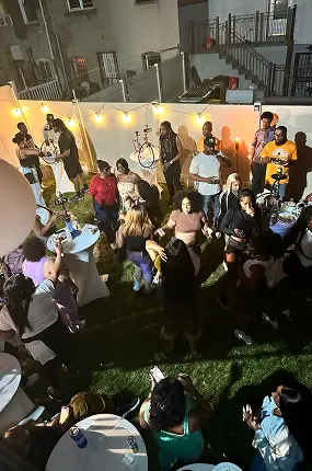 Guests dancing and talking at a night backyard party under string lights with hookah service