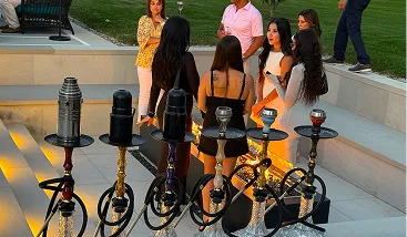 Guests at an outdoor evening party with a row of hookahs set up for hookah catering in NYC