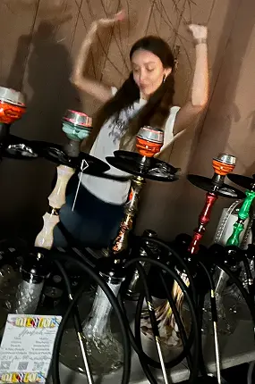 Guest dancing at a house party next to a row of colorful rental hookahs in New York